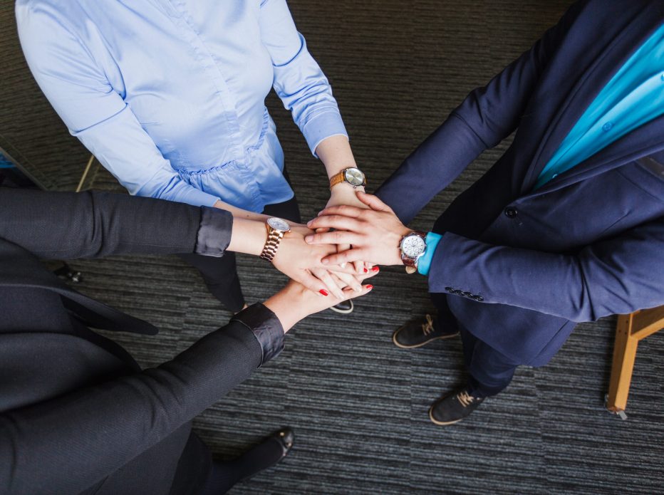 people-standing-office-holding-hands-together